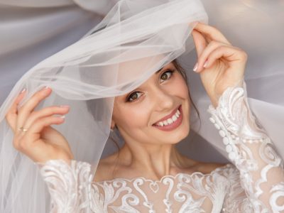 A woman in a wedding dress smiles for the camera while her skin glows post-skincare treatment