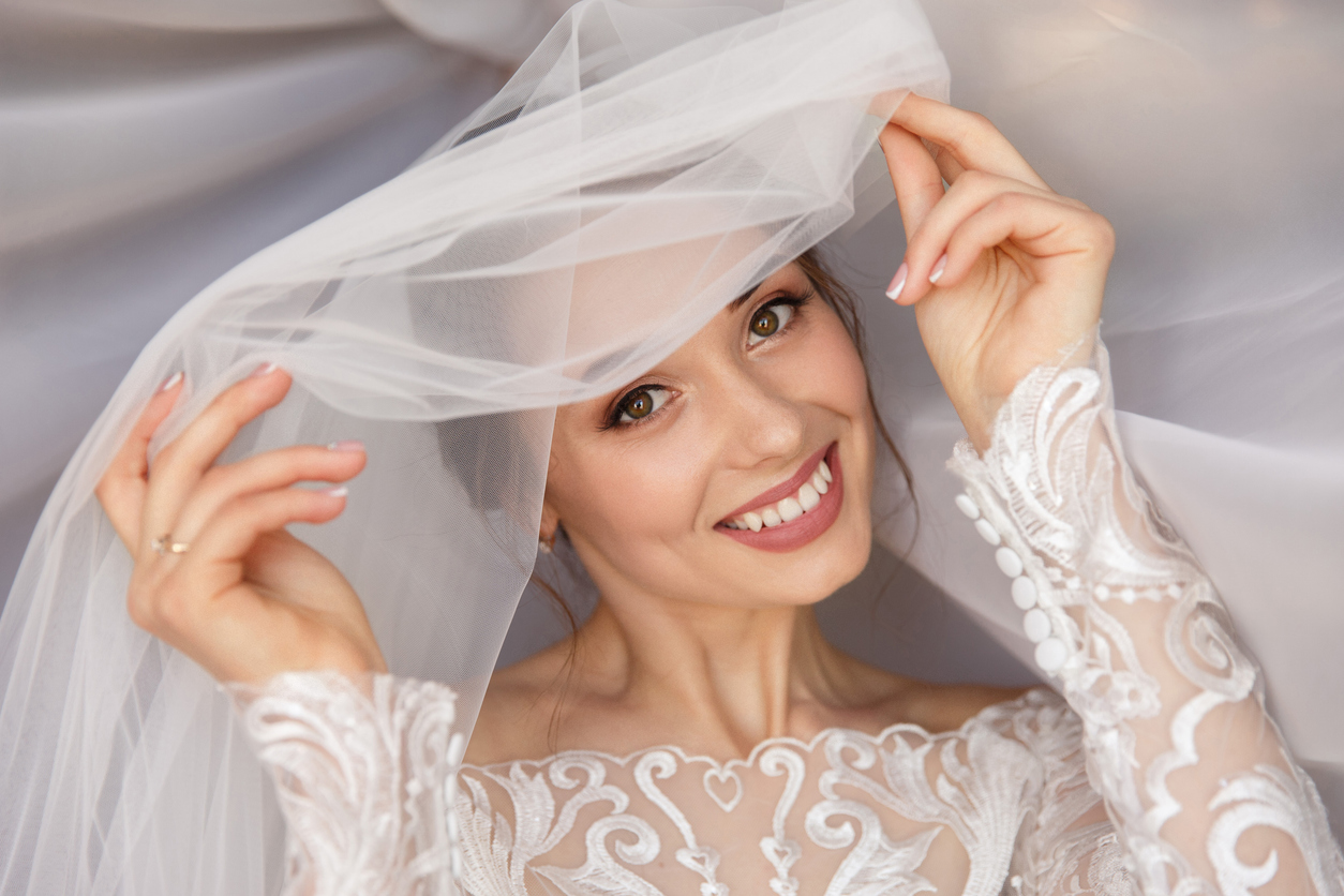 A woman in a wedding dress smiles for the camera while her skin glows post-skincare treatment